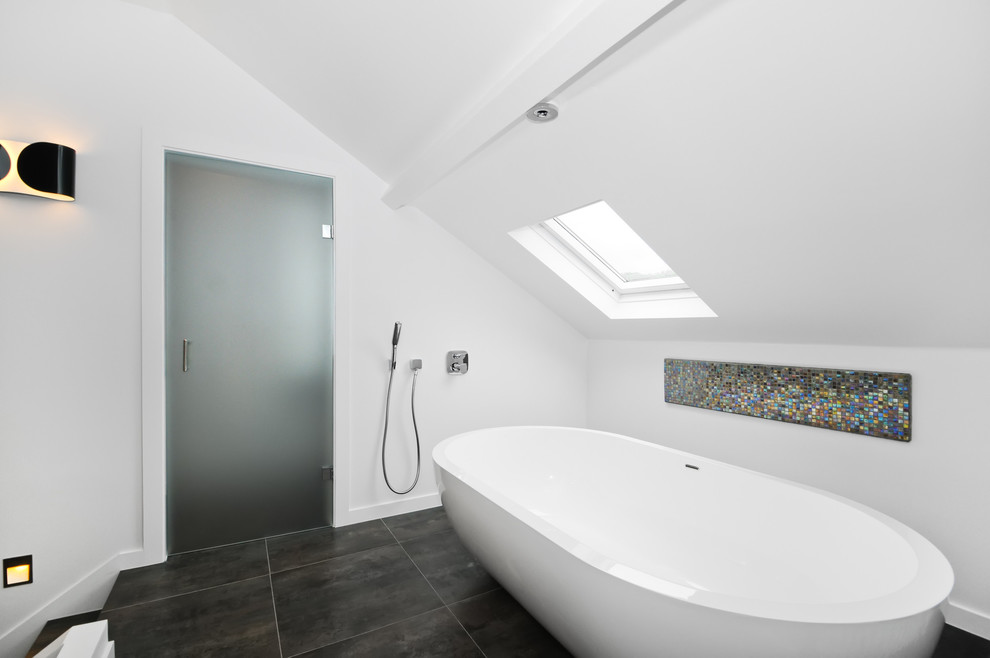 Design ideas for a contemporary bathroom in London with a freestanding bath, a wall mounted toilet and ceramic tiles.