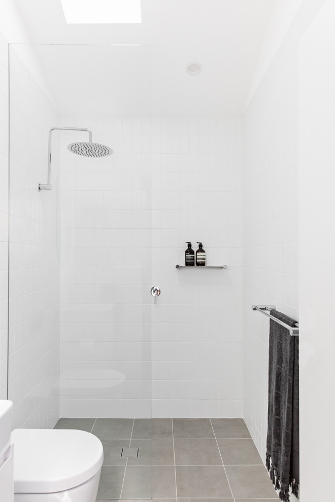 This is an example of a small contemporary master bathroom in Sydney with white cabinets, an open shower, a two-piece toilet, white tile, ceramic tile, white walls, porcelain floors, a wall-mount sink, grey floor, an open shower, a single vanity and a floating vanity.