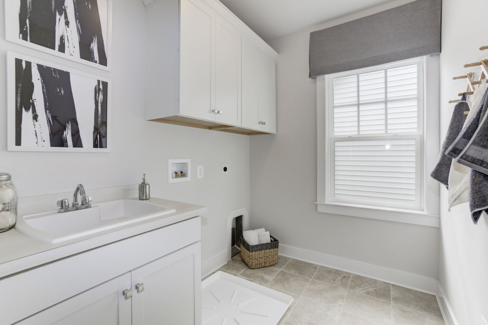 Mid-sized transitional single-wall dedicated laundry room in DC Metro with a drop-in sink, white cabinets, white walls, white benchtop, recessed-panel cabinets, solid surface benchtops, ceramic floors and grey floor.