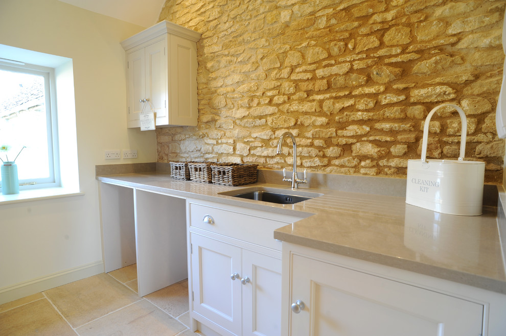 Inspiration for a small traditional single-wall utility room in Gloucestershire with a single-bowl sink, recessed-panel cabinets, quartzite benchtops, limestone floors and a side-by-side washer and dryer.