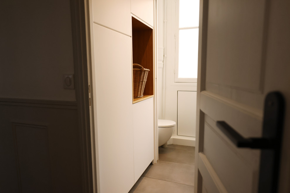 Kleine Moderne Gästetoilette mit Kassettenfronten, weißen Schränken, Wandtoilette, grauen Fliesen, weißer Wandfarbe, Keramikboden, Wandwaschbecken und eingebautem Waschtisch in Paris