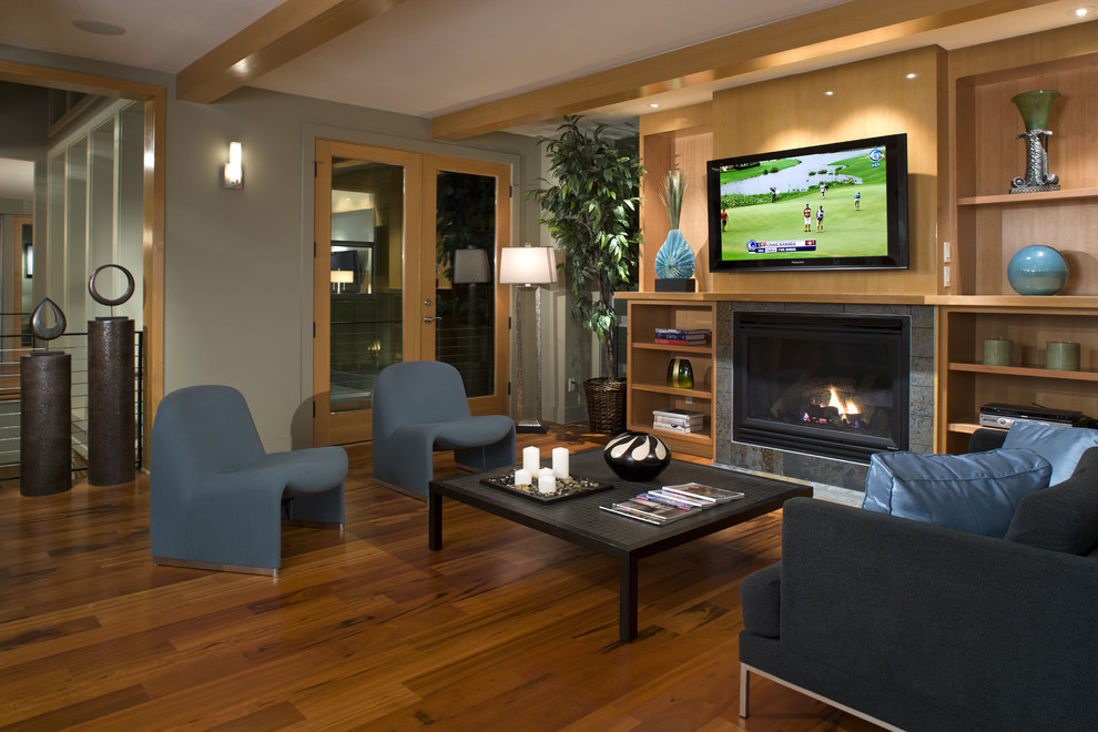 This is an example of a contemporary family room in Seattle with a tile fireplace surround and orange floor.