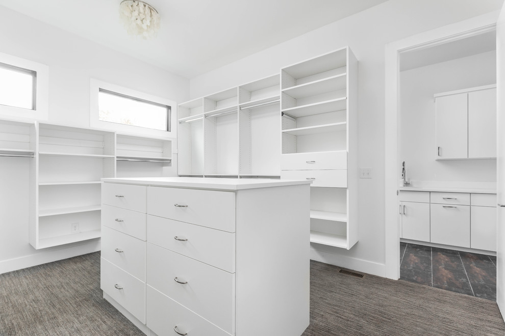 Photo of an expansive modern gender-neutral walk-in wardrobe in Indianapolis with flat-panel cabinets, white cabinets, carpet and grey floor.