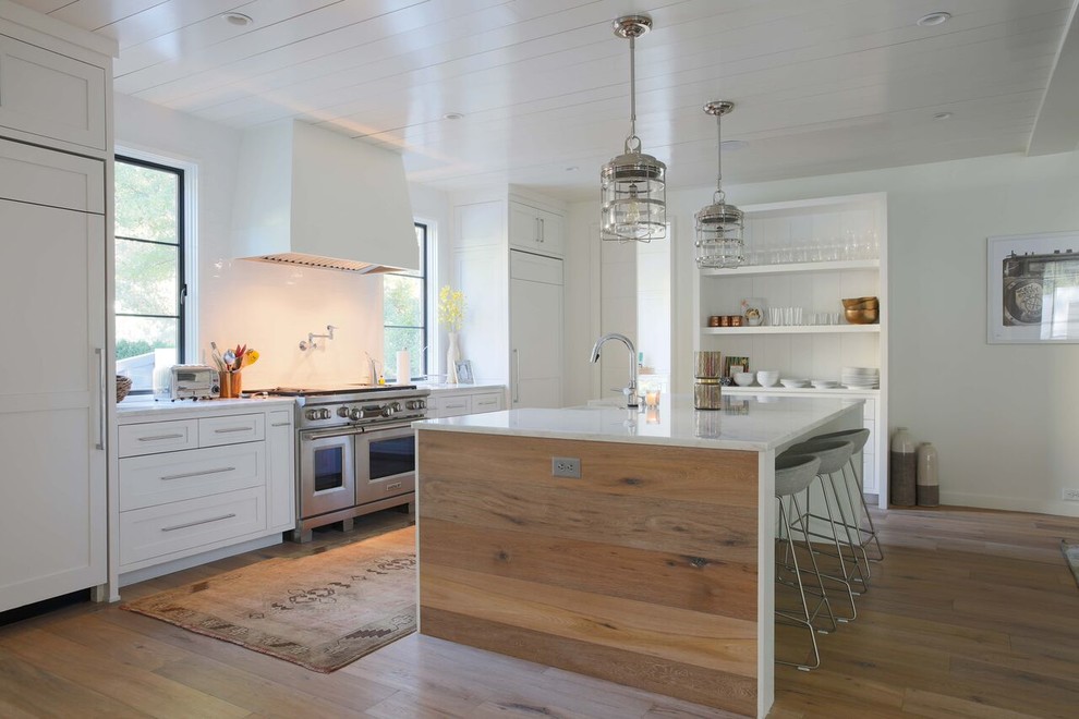 Inspiration for a large modern eat-in kitchen in Charlotte with a drop-in sink, white splashback, stainless steel appliances, light hardwood floors and with island.