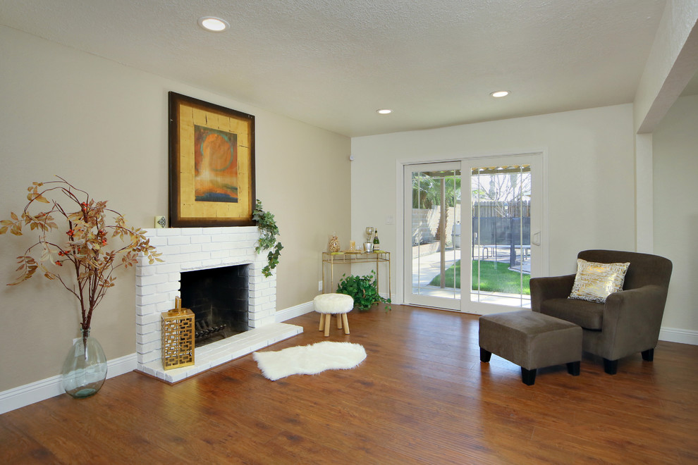Photo of a mid-sized contemporary open concept living room in Sacramento with multi-coloured walls, medium hardwood floors, a standard fireplace, a brick fireplace surround and no tv.