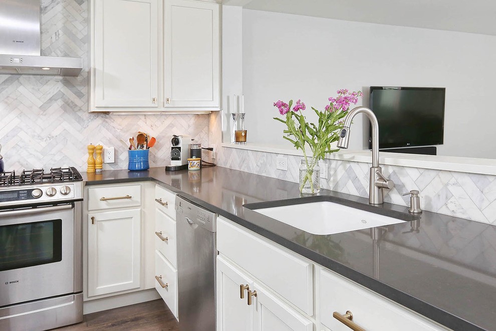 This is an example of a mid-sized transitional l-shaped eat-in kitchen in Philadelphia with an undermount sink, flat-panel cabinets, white cabinets, quartz benchtops, grey splashback, stone tile splashback, stainless steel appliances, dark hardwood floors, with island and brown floor.