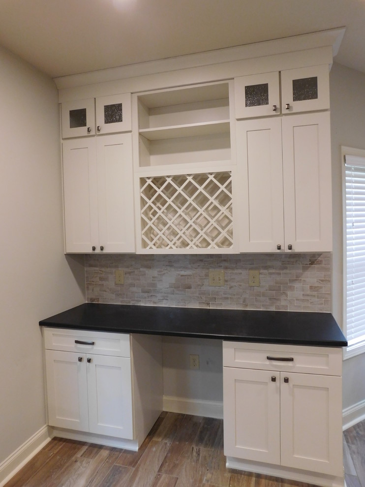This is an example of a small transitional galley eat-in kitchen in Atlanta with a double-bowl sink, shaker cabinets, white cabinets, granite benchtops, grey splashback, stainless steel appliances, light hardwood floors, with island and brown floor.