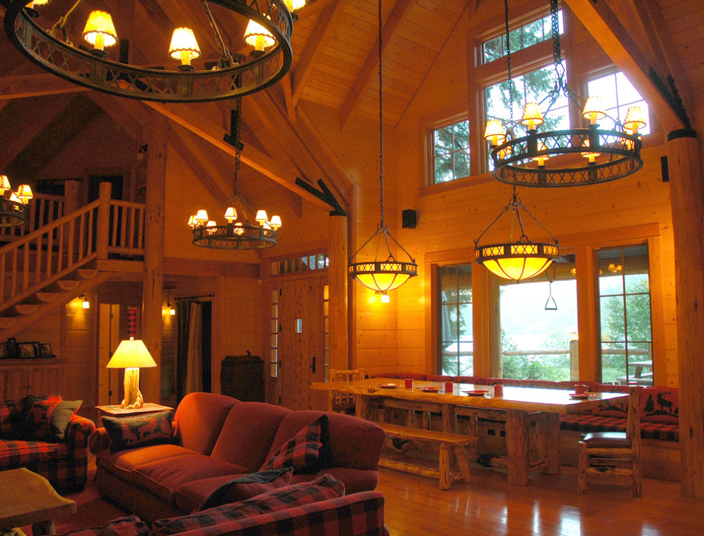 Пример оригинального дизайна: огромная гостиная-столовая в стиле рустика с коричневыми стенами, светлым паркетным полом, сводчатым потолком и деревянными стенами