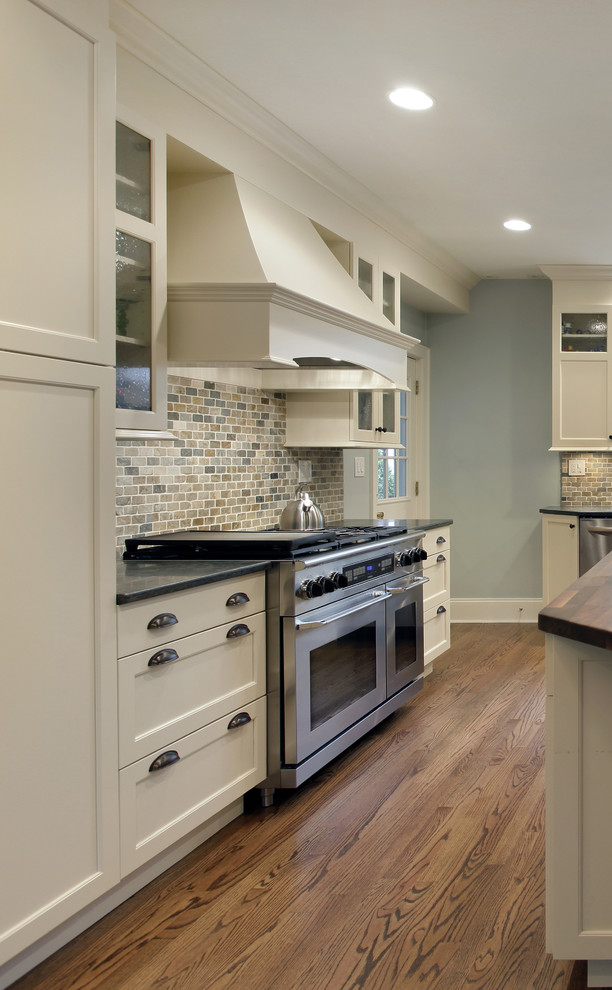 Inspiration for a mid-sized transitional l-shaped medium tone wood floor eat-in kitchen remodel in Toronto with flat-panel cabinets, white cabinets, granite countertops, stainless steel appliances and an island