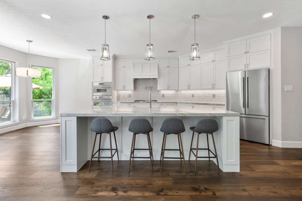 Inspiration for a mid-sized transitional single-wall dark wood floor and brown floor eat-in kitchen remodel in Houston with a farmhouse sink, beaded inset cabinets, white cabinets, quartzite countertops, gray backsplash, ceramic backsplash, stainless steel appliances, an island and gray countertops