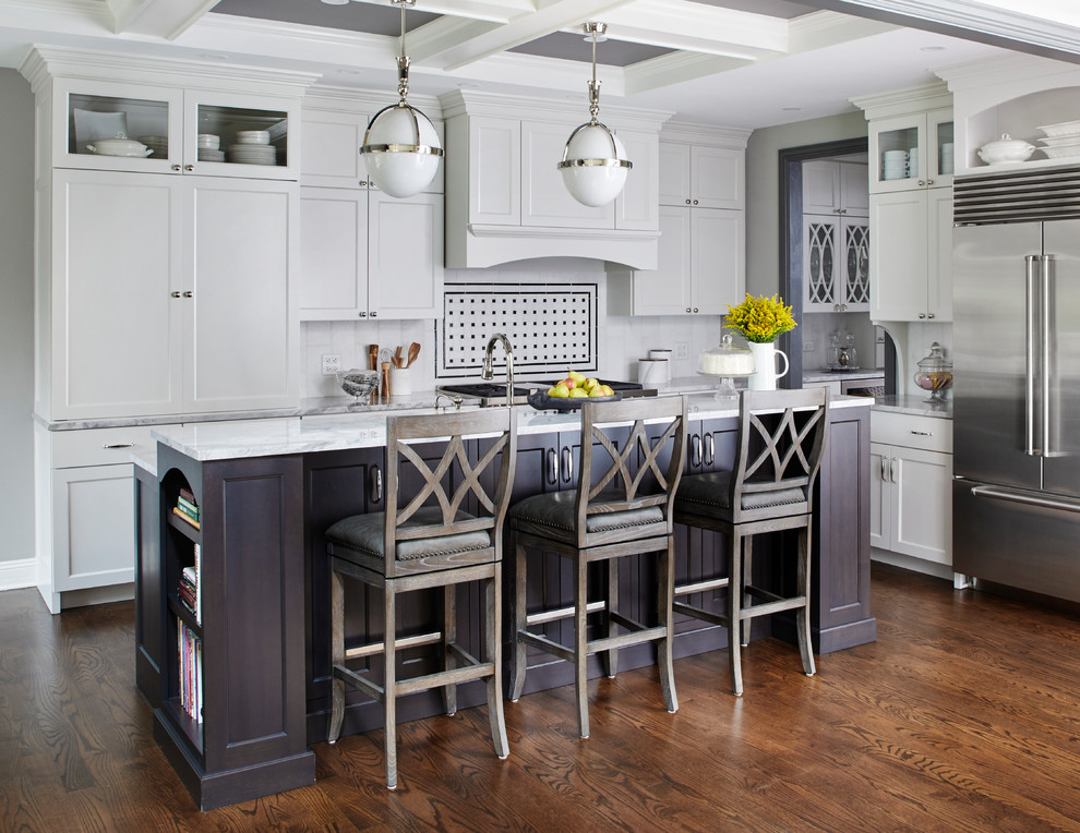 Traditional l-shaped kitchen in Chicago with shaker cabinets, white cabinets, white splashback, stainless steel appliances, dark hardwood floors and with island.