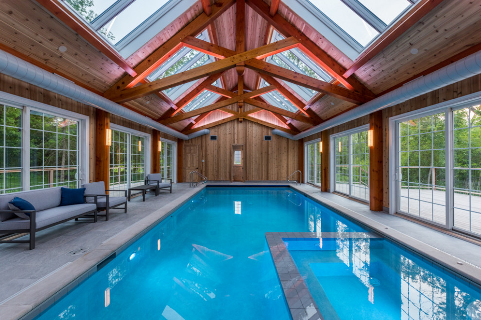 Immagine di una piscina scandinava rettangolare di medie dimensioni e dietro casa con lastre di cemento