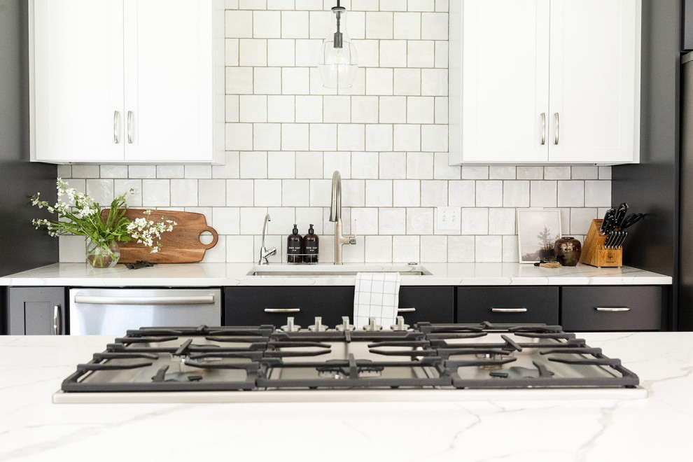 Mid-sized transitional galley vinyl floor and brown floor eat-in kitchen photo with an undermount sink, shaker cabinets, black cabinets, quartz countertops, white backsplash, stainless steel appliances, an island and white countertops