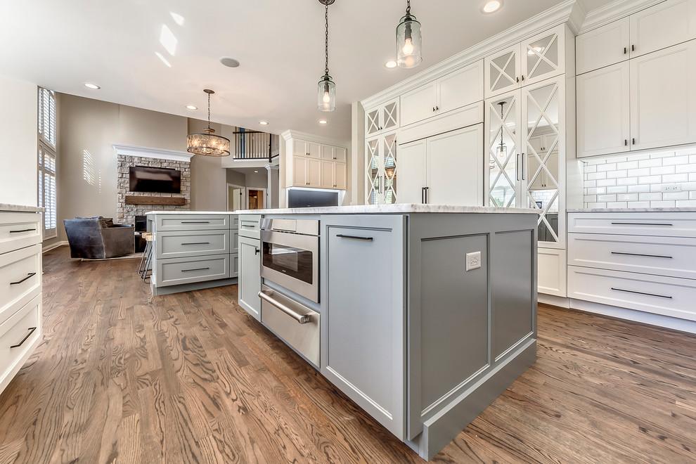 Example of a transitional open concept kitchen design in Chicago with white backsplash, subway tile backsplash and two islands