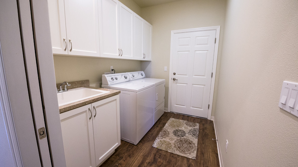 Design ideas for a transitional dedicated laundry room in Portland with an utility sink, shaker cabinets, white cabinets, laminate benchtops, beige walls, vinyl floors and a side-by-side washer and dryer.