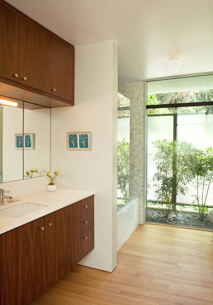 Large midcentury bathroom in Los Angeles with flat-panel cabinets, medium wood cabinets, an alcove tub, a shower/bathtub combo, gray tile, white tile, mosaic tile, white walls, light hardwood floors, an undermount sink, beige floor, an open shower and white benchtops.