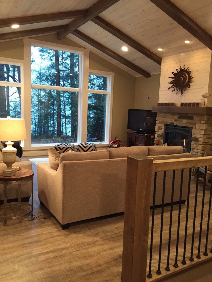 Mid-sized transitional l-shaped and open concept medium tone wood floor and brown floor living room photo with shaker cabinets, an island, beige walls, a standard fireplace, a stone fireplace and a tv stand