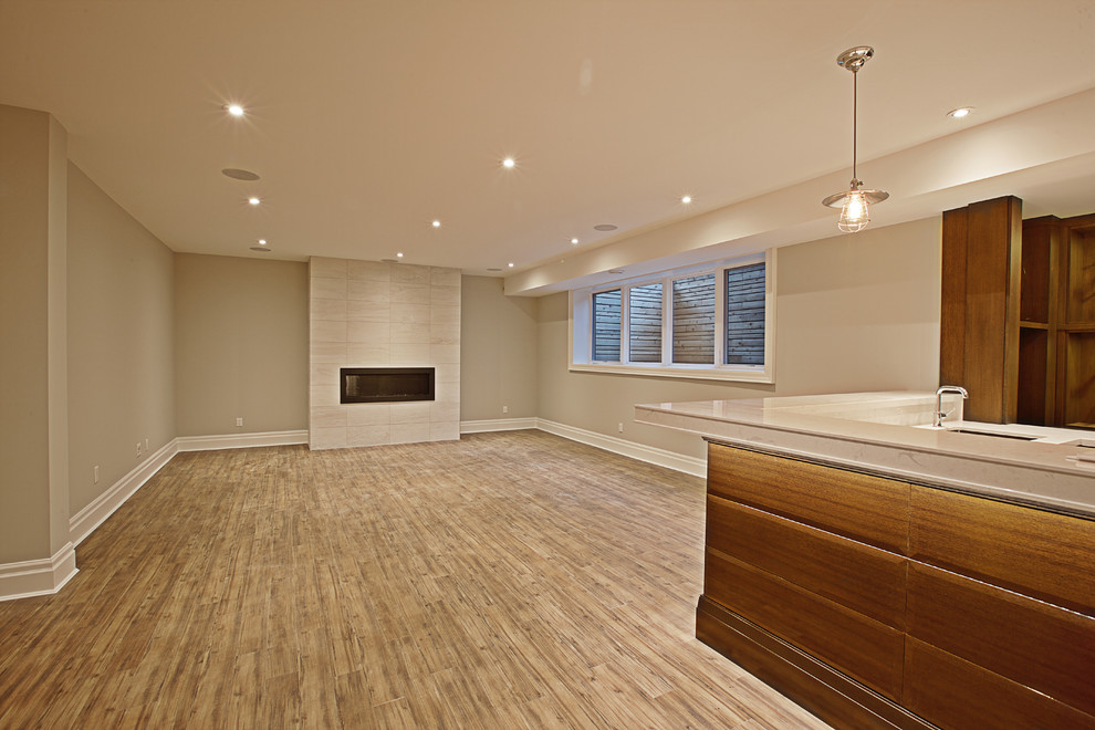 Example of a mid-sized transitional open concept vinyl floor and brown floor basement game room design in Toronto with gray walls and a standard fireplace