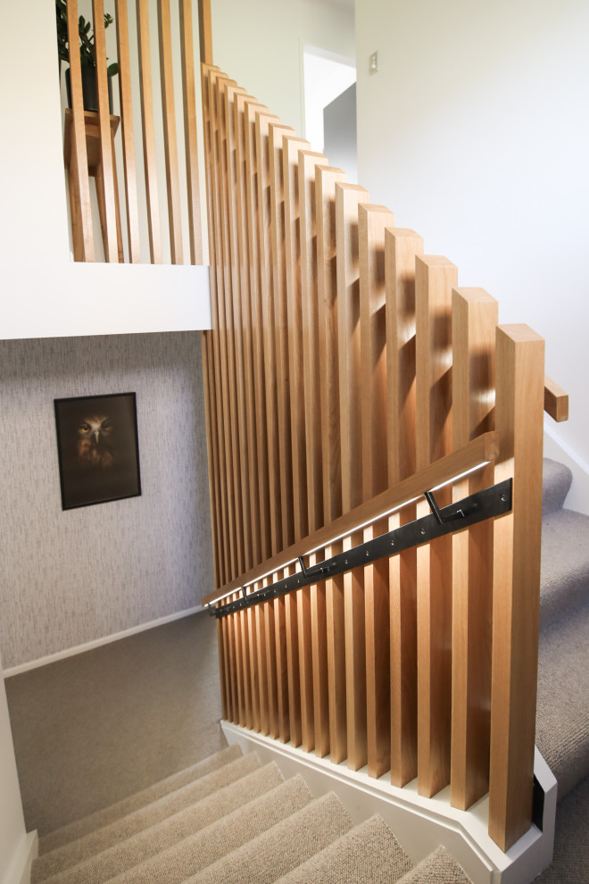 Aménagement d'un escalier droit contemporain de taille moyenne avec des marches en moquette, un garde-corps en bois et du papier peint.