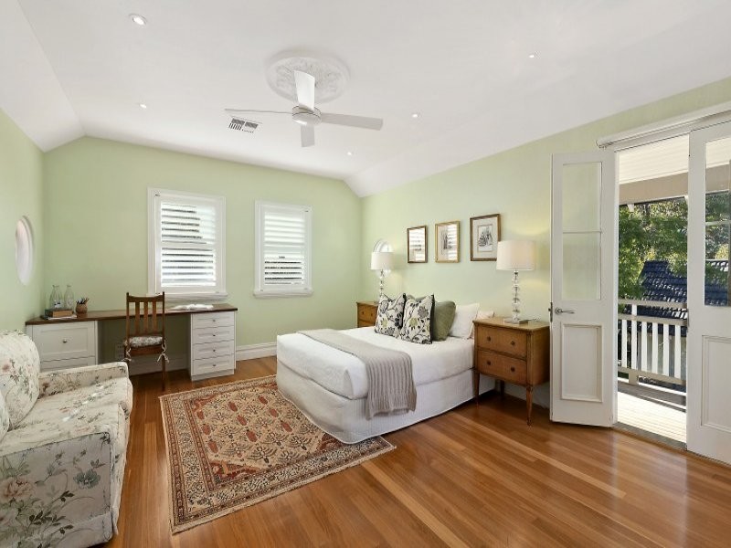 This is an example of a large traditional guest bedroom in Sydney with green walls and medium hardwood floors.