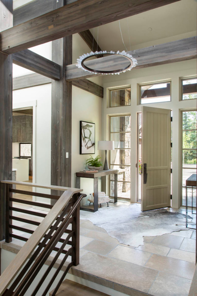 Single front door - rustic limestone floor, beige floor and exposed beam single front door idea with beige walls and a light wood front door