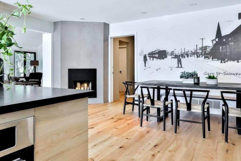 This is an example of a large contemporary dining room in Montreal with white walls, light hardwood floors, a corner fireplace, a concrete fireplace surround and wallpaper.