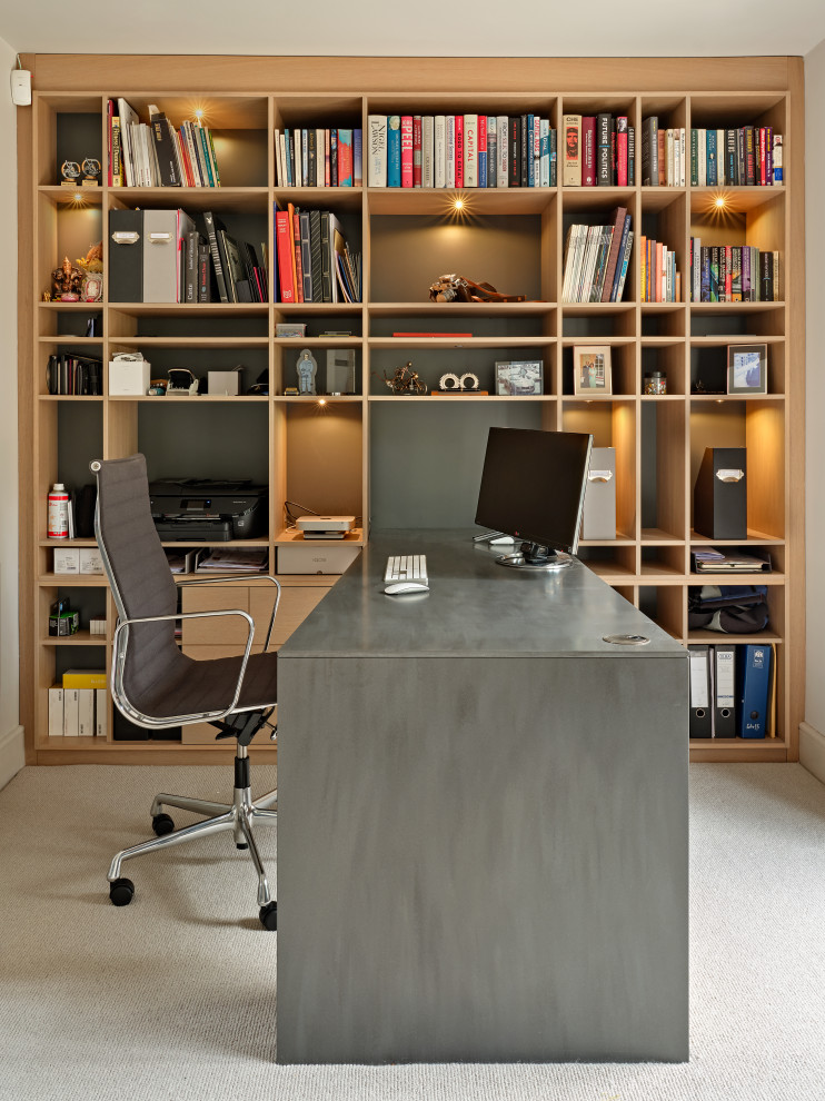 This is an example of a small modern study room in Surrey with carpet, no fireplace, a built-in desk and beige floor.