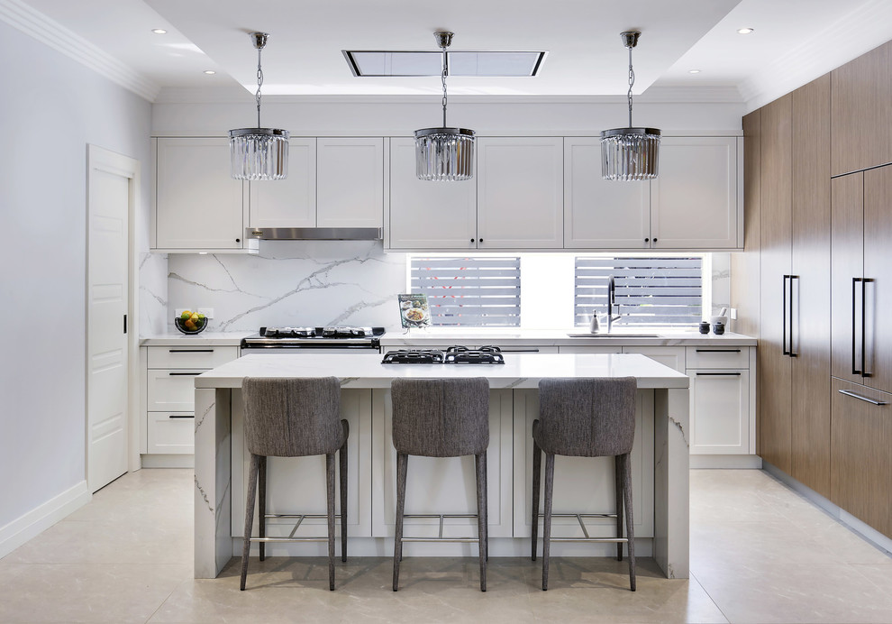 Photo of a large modern l-shaped eat-in kitchen in Sydney with a double-bowl sink, shaker cabinets, white cabinets, quartz benchtops, white splashback, stone tile splashback, coloured appliances, limestone floors, with island and beige floor.