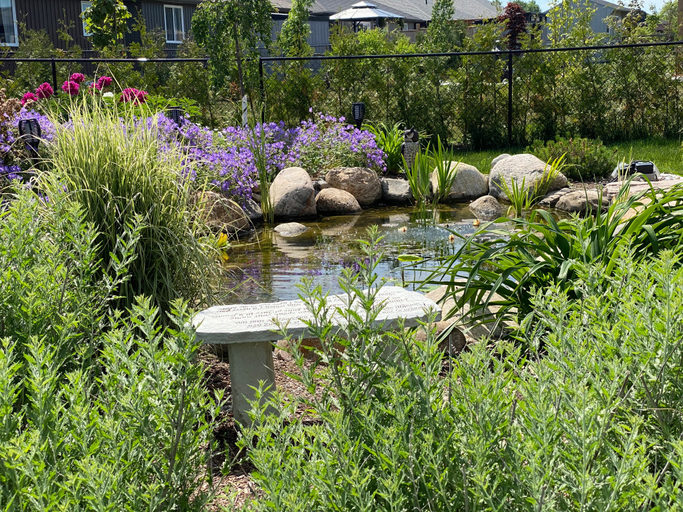 This is an example of a mid-sized country backyard full sun garden in Other with with pond.