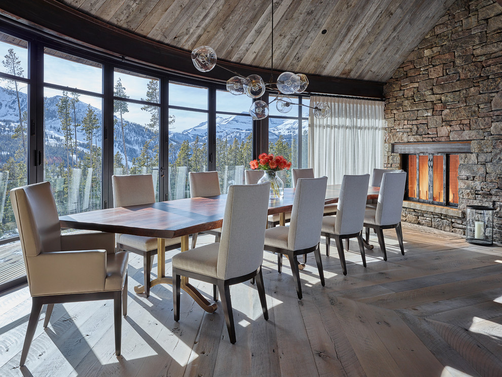 This is an example of a large country separate dining room in Other with medium hardwood floors, a standard fireplace, a stone fireplace surround and brown walls.