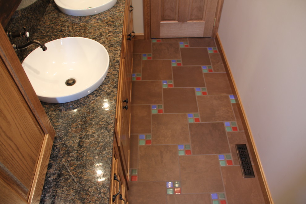 Tub/shower combo - transitional brown tile and porcelain tile porcelain tile tub/shower combo idea in Columbus with a vessel sink, an undermount tub, a two-piece toilet, raised-panel cabinets, medium tone wood cabinets, granite countertops and beige walls