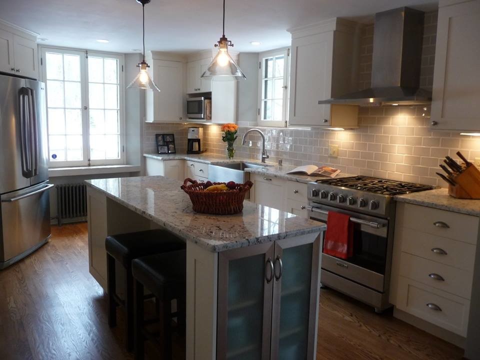 Large transitional u-shaped light wood floor eat-in kitchen photo in Milwaukee with a farmhouse sink, recessed-panel cabinets, white cabinets, granite countertops, gray backsplash, subway tile backsplash, stainless steel appliances and an island