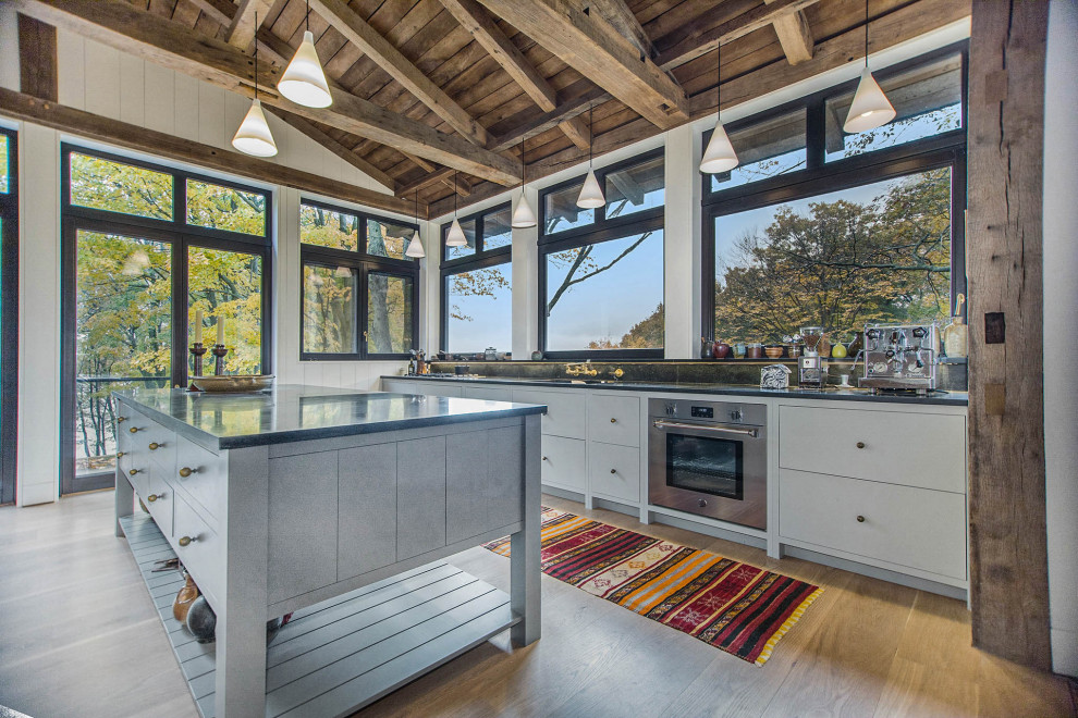 Mountain style single-wall exposed beam eat-in kitchen photo in Grand Rapids with an undermount sink, flat-panel cabinets, gray cabinets, stainless steel appliances, an island and black countertops