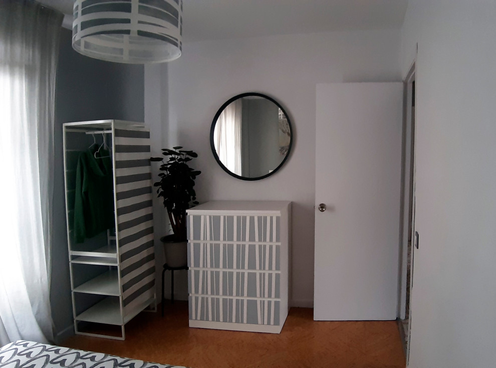 Cette photo montre une petite chambre d'amis grise et blanche moderne avec un sol en liège.
