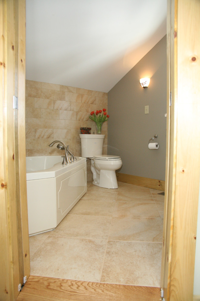 This is an example of a small traditional master bathroom in New York with recessed-panel cabinets, dark wood cabinets, granite benchtops, a corner tub, a wall-mount toilet, beige tile, ceramic tile, beige walls, ceramic floors and an undermount sink.