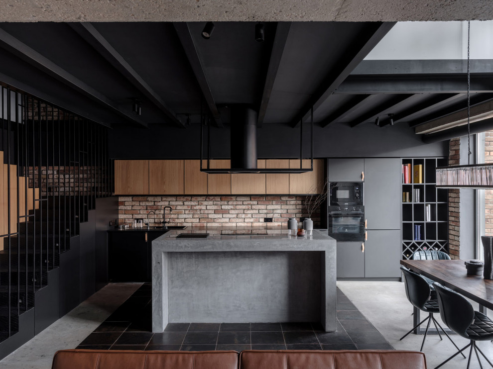 Photo of an industrial galley open plan kitchen in Moscow with flat-panel cabinets, medium wood cabinets, red splashback, brick splashback, black appliances, concrete floors, with island, grey floor, grey benchtop and exposed beam.