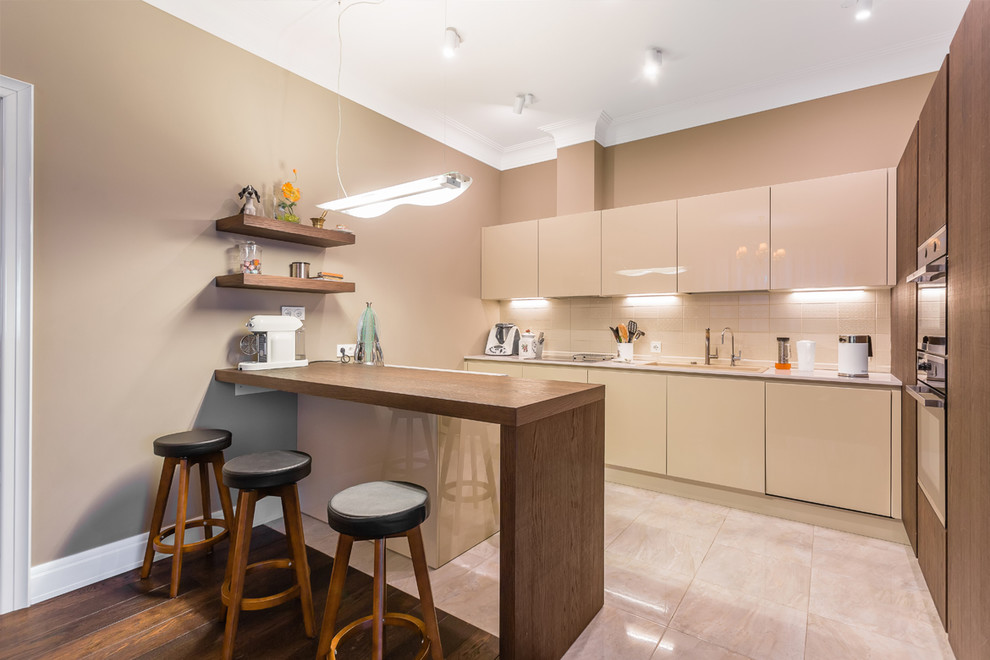 Design ideas for a large transitional l-shaped eat-in kitchen in Moscow with an undermount sink, flat-panel cabinets, beige cabinets, quartz benchtops, beige splashback, ceramic splashback, stainless steel appliances, porcelain floors, beige floor and beige benchtop.