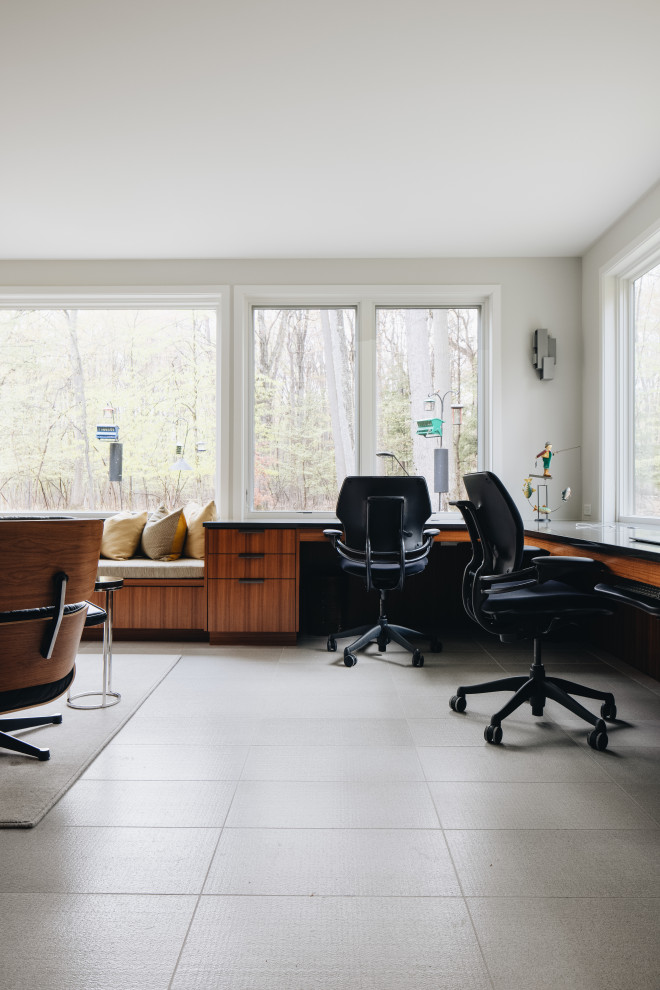 グランドラピッズにある広いミッドセンチュリースタイルのおしゃれなホームオフィス・書斎 (ベージュの壁、磁器タイルの床、造り付け机、グレーの床) の写真
