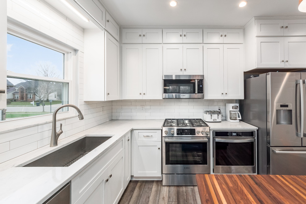 Eat-in kitchen - mid-sized transitional l-shaped eat-in kitchen idea in Columbus with shaker cabinets, quartz countertops, white backsplash, subway tile backsplash and an island