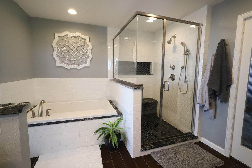 Photo of a mid-sized modern master bathroom in Denver with glass-front cabinets, white cabinets, a drop-in tub, an alcove shower, a bidet, white tile, porcelain tile, grey walls, porcelain floors, an undermount sink, soapstone benchtops, brown floor, a hinged shower door and black benchtops.