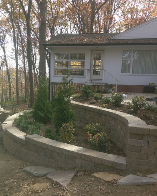 This is an example of a large shade front yard concrete paver retaining wall landscape.