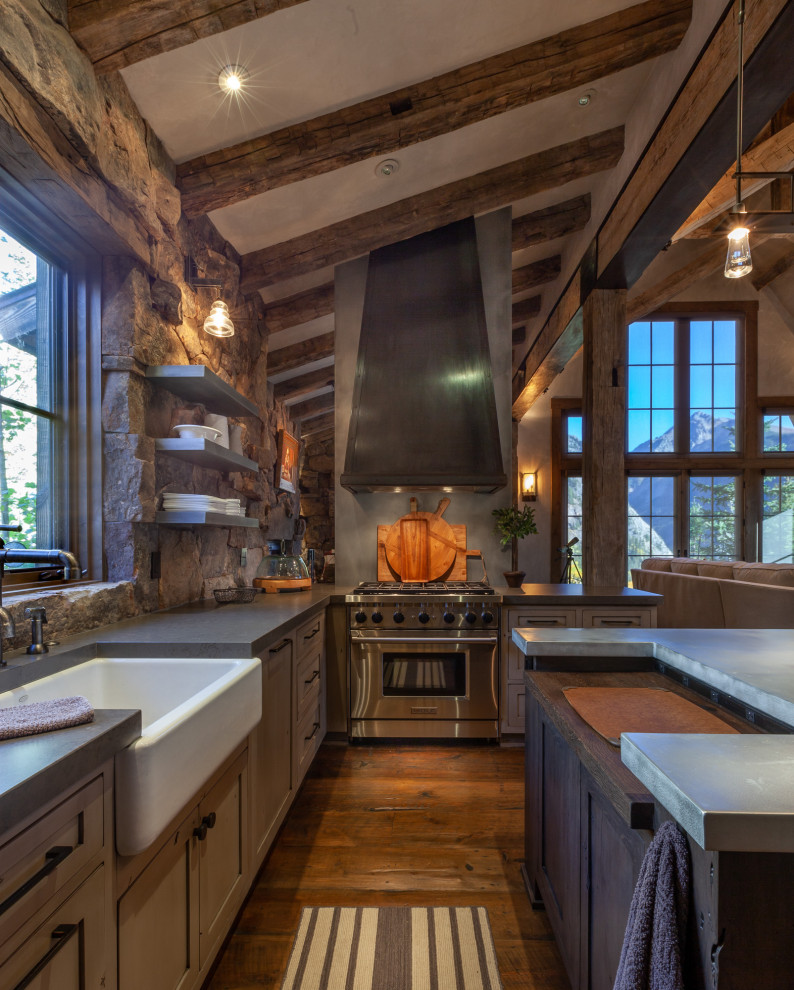 Inspiration for a mid-sized country u-shaped separate kitchen in Denver with a farmhouse sink, shaker cabinets, dark hardwood floors, with island, brown floor, grey benchtop, distressed cabinets, concrete benchtops, brown splashback, stone tile splashback, panelled appliances and exposed beam.