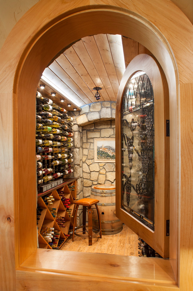 Design ideas for a mid-sized country wine cellar in Denver with light hardwood floors, display racks and beige floor.