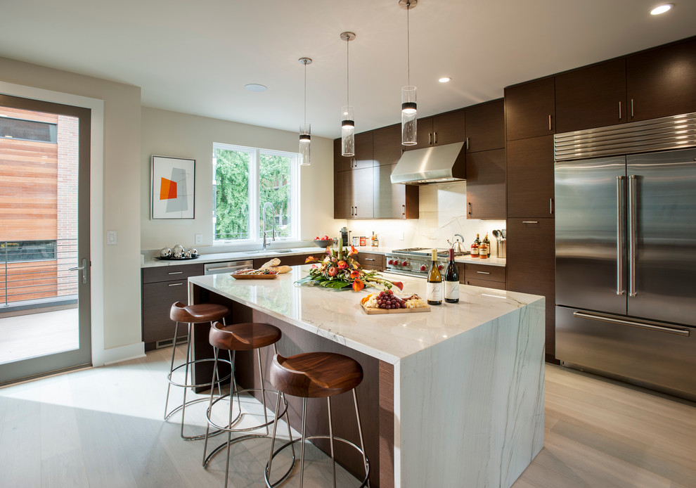 Photo of a contemporary l-shaped open plan kitchen in Philadelphia with flat-panel cabinets, dark wood cabinets, marble benchtops, white splashback, stone tile splashback, stainless steel appliances, light hardwood floors and with island.