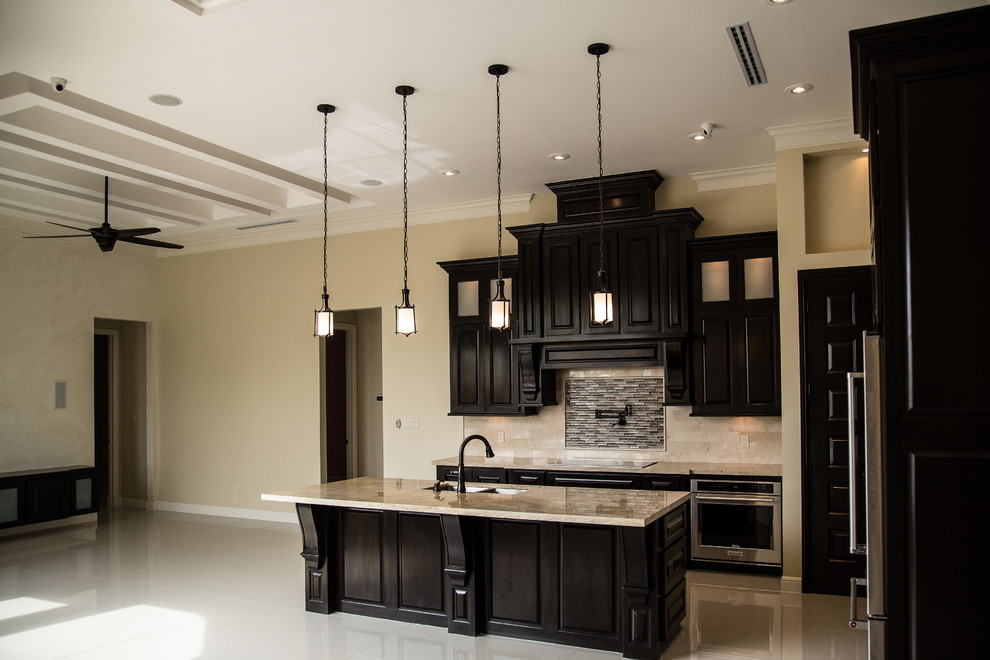 Eat-in kitchen - large transitional l-shaped porcelain tile eat-in kitchen idea in Austin with an undermount sink, raised-panel cabinets, dark wood cabinets, granite countertops, beige backsplash, subway tile backsplash, stainless steel appliances and an island