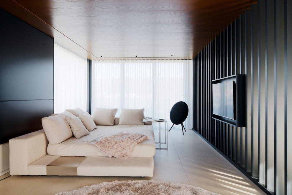 This is an example of an expansive contemporary enclosed home theatre in Berlin with black walls, marble floors, a wall-mounted tv and brown floor.
