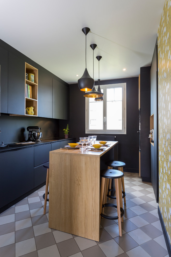 Photo of a large contemporary galley separate kitchen in Paris with an integrated sink, black splashback, stainless steel appliances, with island, grey floor and black benchtop.