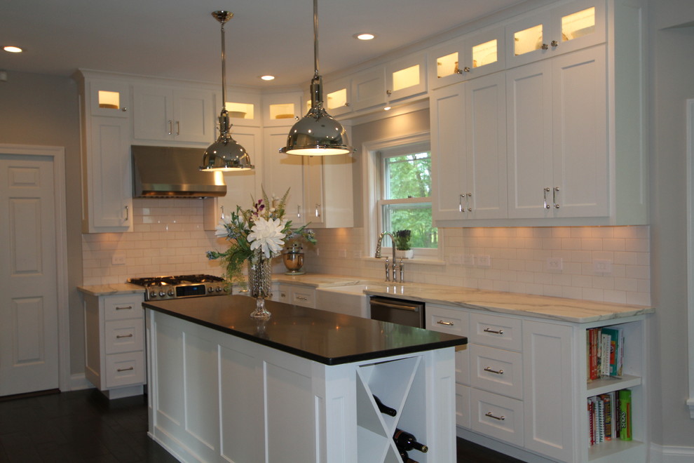 Transitional dark wood floor eat-in kitchen photo with a farmhouse sink, flat-panel cabinets, white cabinets, marble countertops, white backsplash, subway tile backsplash, stainless steel appliances and an island