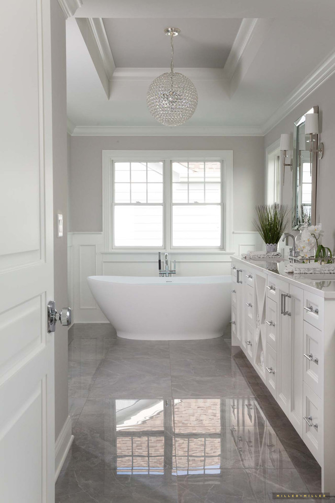 This is an example of a large country master bathroom in Chicago with shaker cabinets, white cabinets, a freestanding tub, grey walls, a drop-in sink, solid surface benchtops, grey floor and white benchtops.