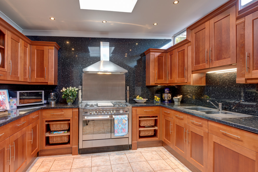 Photo of a transitional kitchen in Devon with a drop-in sink, shaker cabinets, medium wood cabinets, granite benchtops, black splashback, stone slab splashback and stainless steel appliances.